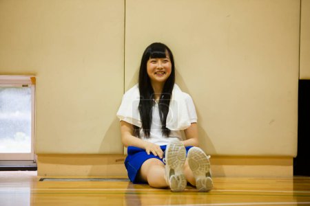 Téléchargez les photos : Jeune femme asiatique assis sur le sol dans la salle de gym - en image libre de droit