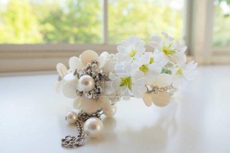 Photo for White flowers and jewelry with pearls on white windowsill - Royalty Free Image