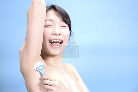 Foto de Primer plano de las axilas de afeitar hembra asiática quitar el pelo axilas con afeitadora de seguridad - Imagen libre de derechos