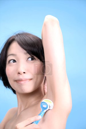 Téléchargez les photos : Gros plan de femmes asiatiques rasage aisselles enlèvement des aisselles cheveux avec rasoir de sécurité - en image libre de droit