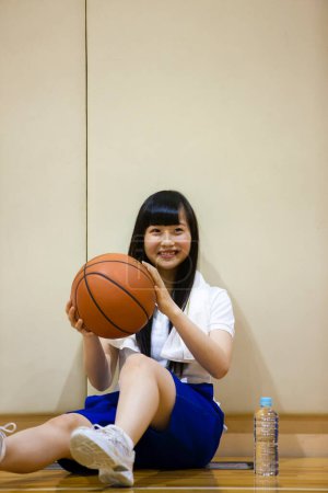 Photo for Cute asian girl  sitting on basketball court - Royalty Free Image