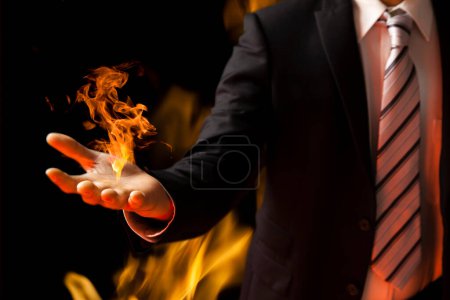 Foto de Empresario en traje sosteniendo la llama sobre fondo negro - Imagen libre de derechos