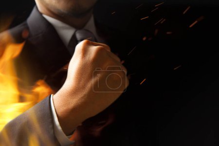 Photo for Businessman in suit holding flame over black background - Royalty Free Image