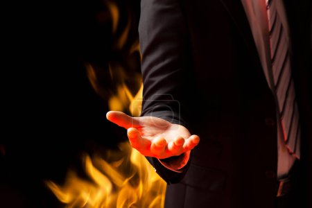 Téléchargez les photos : Homme d'affaires en costume tenant la flamme sur fond noir - en image libre de droit