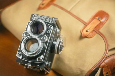 Photo for Old twin lens reflex camera Rolleiflex in front of brown leather handbag - Royalty Free Image