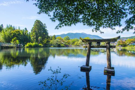 Lake Kinrin and Japanese gate (Torii) with mountain Yufu and blue sky background at Yufuin, Oita, Kyushu, Japan