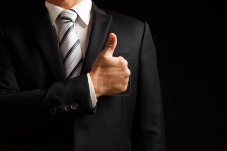 Photo for Male business man showing thumb up on black background - Royalty Free Image