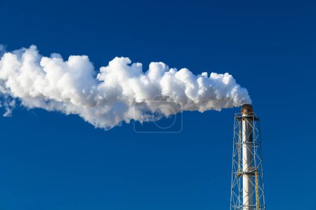 Photo for White smoke from  factory chimney against blue sky - Royalty Free Image
