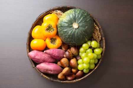 Foto de Concepto de cosecha fondo con tomates frescos, patatas, bayas de uva y calabaza verde - Imagen libre de derechos