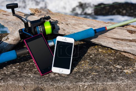 Foto de Smartphones y caña de pescar en la orilla del mar - Imagen libre de derechos