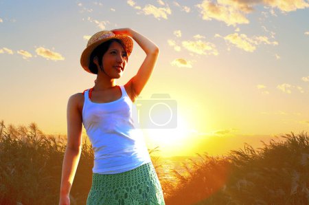 Téléchargez les photos : Jeune femme portant un chapeau de paille contre la mer au coucher du soleil - en image libre de droit