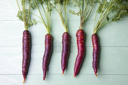 Photo for Bunch of fresh purple carrots on wooden table - Royalty Free Image