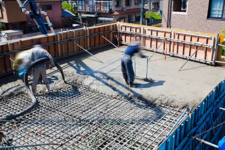 Téléchargez les photos : Travailleur coulant du ciment pour la fabrication de plancher sur le chantier de construction - en image libre de droit
