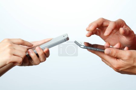 Foto de Dos manos sosteniendo teléfonos inteligentes aislados sobre fondo blanco - Imagen libre de derechos