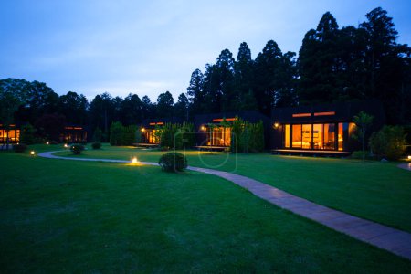 Photo for Exterior of modern cottage house with green grassy lawn in the evening - Royalty Free Image
