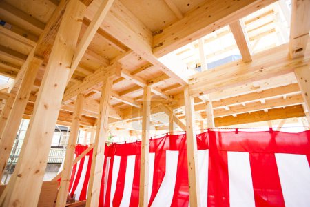 Photo for New house under construction. Wooden beams decorated with red and white striped textile for building completion ceremony - Royalty Free Image