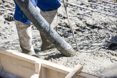 Foto de Trabajador vertiendo cemento para hacer piso en el sitio de construcción - Imagen libre de derechos
