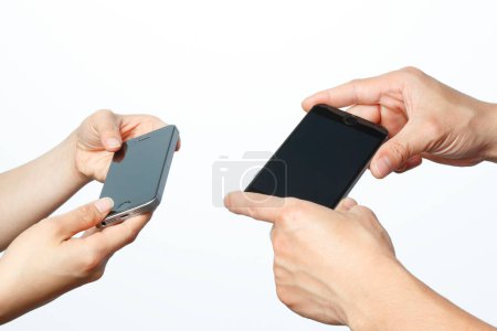Téléchargez les photos : Deux mains tenant des smartphones isolés sur fond blanc - en image libre de droit