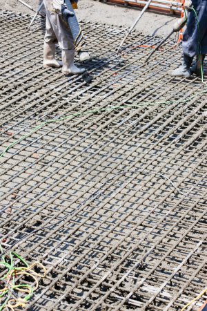 Foto de Trabajadores que utilizan refuerzo de acero para hacer piso en obra - Imagen libre de derechos