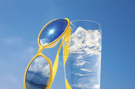 Téléchargez les photos : Verre d'eau avec glaçons et lunettes de soleil jaunes sur le fond du ciel bleu, concept de vacances d'été et de détente dans une journée ensoleillée, espace de copie - en image libre de droit