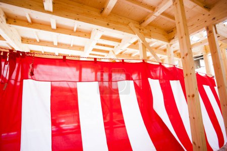 Foto de Nueva casa en construcción. Vigas de madera decoradas con textiles a rayas rojas y blancas para la ceremonia de finalización del edificio - Imagen libre de derechos