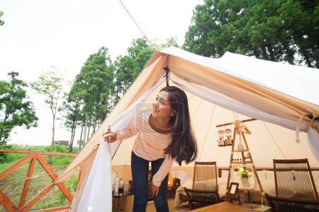 Photo for Happy young Asian woman looking out of her tent in summer forest - Royalty Free Image