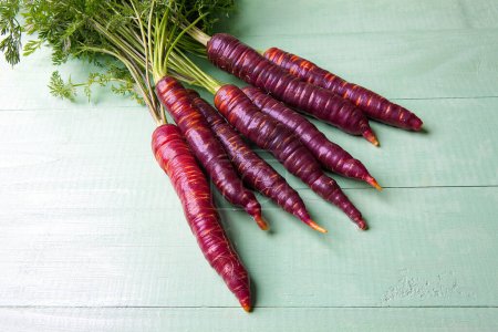 Téléchargez les photos : Bouquet de carottes violettes fraîches sur table en bois - en image libre de droit