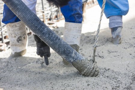 Foto de Trabajador vertiendo cemento para hacer piso en el sitio de construcción - Imagen libre de derechos