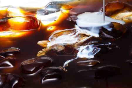Photo for Macro shot of milk poured into ice coffee - Royalty Free Image
