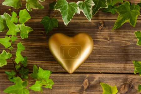 Foto de Corazón dorado con hojas sobre fondo de madera. concepto de día de San Valentín - Imagen libre de derechos