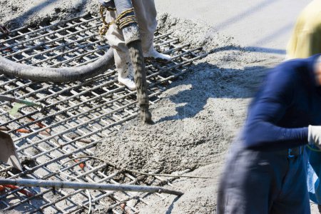 Téléchargez les photos : Travailleur coulant du ciment pour la fabrication de plancher sur le chantier de construction - en image libre de droit