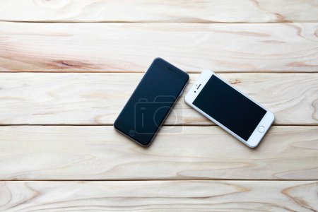 Foto de Dos teléfonos inteligentes con pantallas en blanco en escritorio de madera. - Imagen libre de derechos