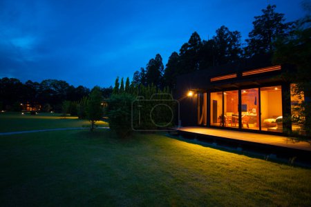Foto de Exterior de la casa de campo moderna con césped verde herboso por la noche - Imagen libre de derechos