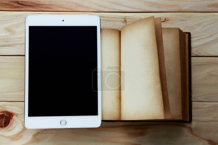 Photo for Tablet pc with black screen and old book with blank pages on wooden background - Royalty Free Image
