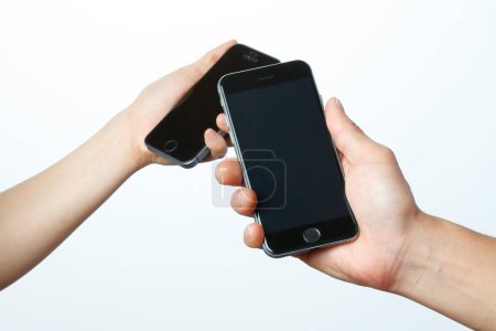 Foto de Dos manos sosteniendo teléfonos inteligentes aislados sobre fondo blanco - Imagen libre de derechos