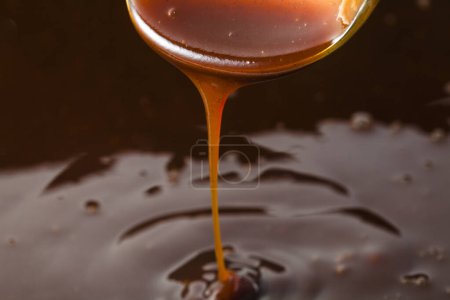 Photo for Pouring chocolate syrup from a spoon. - Royalty Free Image