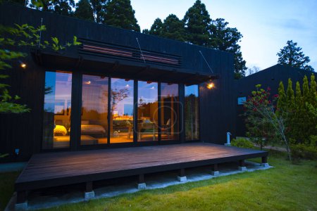 Téléchargez les photos : Extérieur de la maison de campagne moderne avec pelouse verdoyante le soir - en image libre de droit