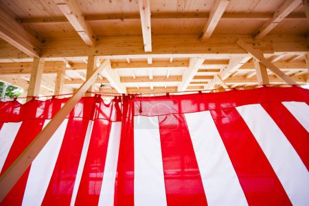 Photo for New house under construction. Wooden beams decorated with red and white striped textile for building completion ceremony - Royalty Free Image