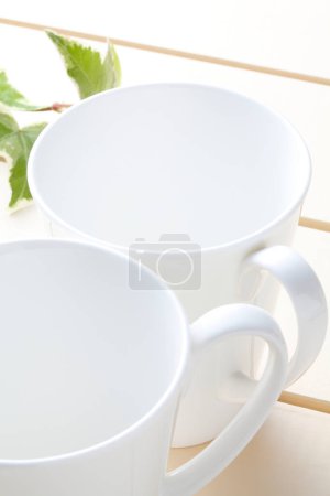 Téléchargez les photos : Tasses blanches vides pour thé ou thé chaud sur une table blanche - en image libre de droit