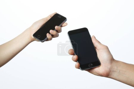 Téléchargez les photos : Deux mains tenant des smartphones isolés sur fond blanc - en image libre de droit