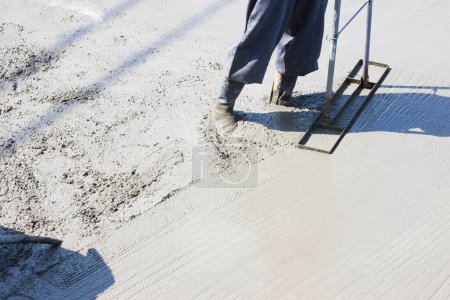 Téléchargez les photos : Travailleur utilisant du ciment pour la fabrication de plancher sur le chantier - en image libre de droit