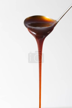 Photo for Close up view of sweet caramel pouring on white background - Royalty Free Image