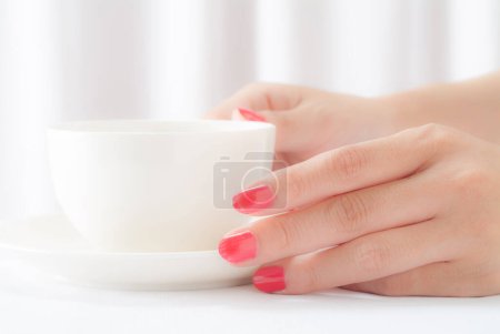 Téléchargez les photos : Main féminine avec des ongles rouges tenant tasse de café - en image libre de droit