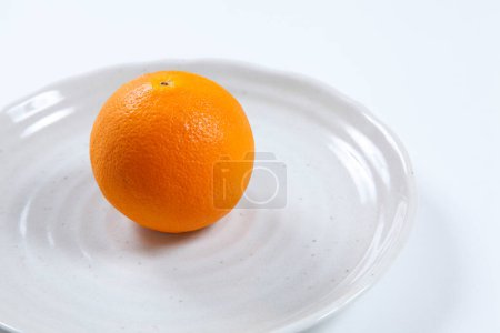 Téléchargez les photos : Orange entière sur une assiette blanche - en image libre de droit