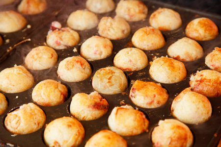 Téléchargez les photos : Cuisson Takoyaki, collations japonaises en forme de boule faites d'une pâte à base de farine de blé et cuites dans une casserole moulée spéciale - en image libre de droit