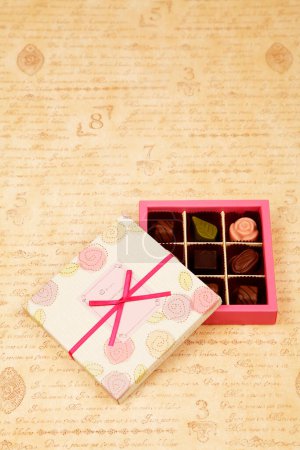 Téléchargez les photos : Bonbons au chocolat en boîte avec un noeud sur le fond, gros plan - en image libre de droit