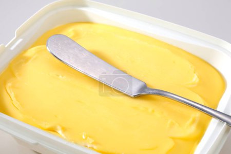 Photo for Knife and butter in plastic container on white background - Royalty Free Image