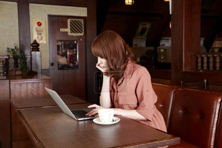 Foto de Pelirroja japonesa que trabaja en la cafetería. Retrato de mujer de negocios de belleza utilizando el ordenador portátil - Imagen libre de derechos