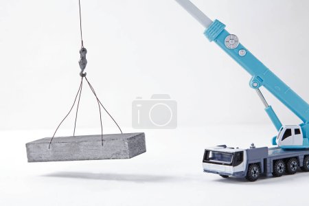 Foto de Juguete grúa azul cargando un bloque de hormigón sobre fondo blanco. Mock-up - Imagen libre de derechos