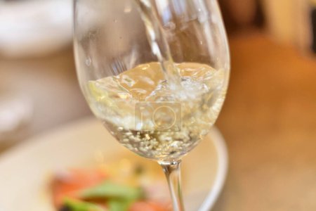 Téléchargez les photos : Verre à vin avec vin blanc sur une table en bois dans un café - en image libre de droit